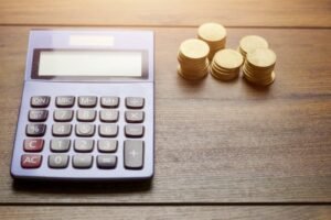 calculadora con billetes y monedas sobre mesa