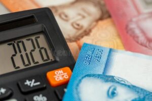 calculadora y billetes chilenos sobre mesa madera