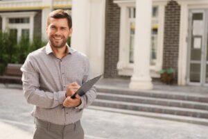 joven solo sonriente frente a casa moderna