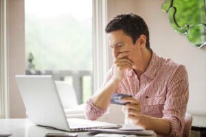 persona usando tarjeta de credito en computadora